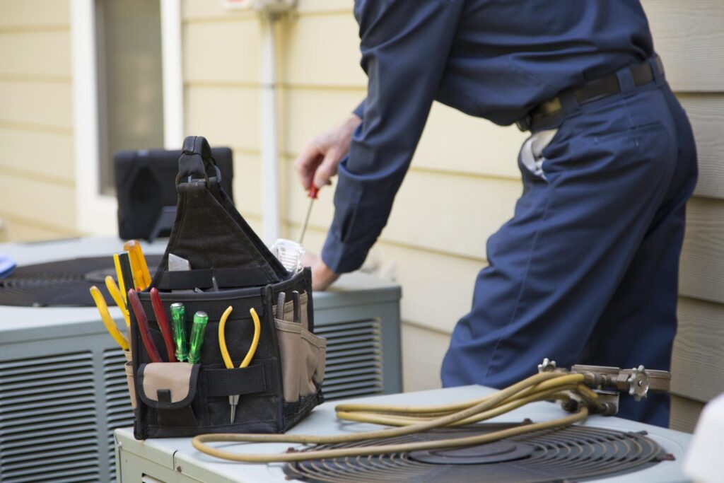 HVAC technician performing spring air conditioner maintenance to prevent freeze-ups before summer