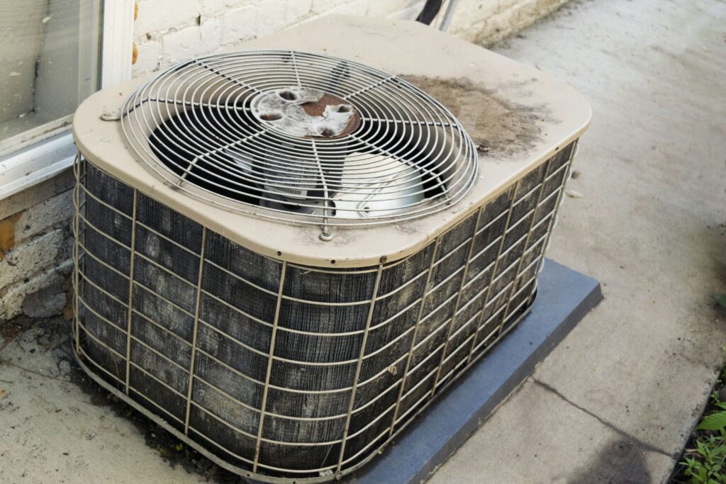 Aging outdoor air conditioner condenser unit being assessed for repair or replacement